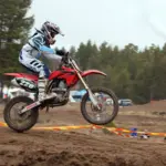 Motocross rider wearing a helmet and boots while jumping a dirt motorcycle