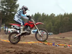 Motocross rider wearing a helmet and boots while jumping a dirt motorcycle