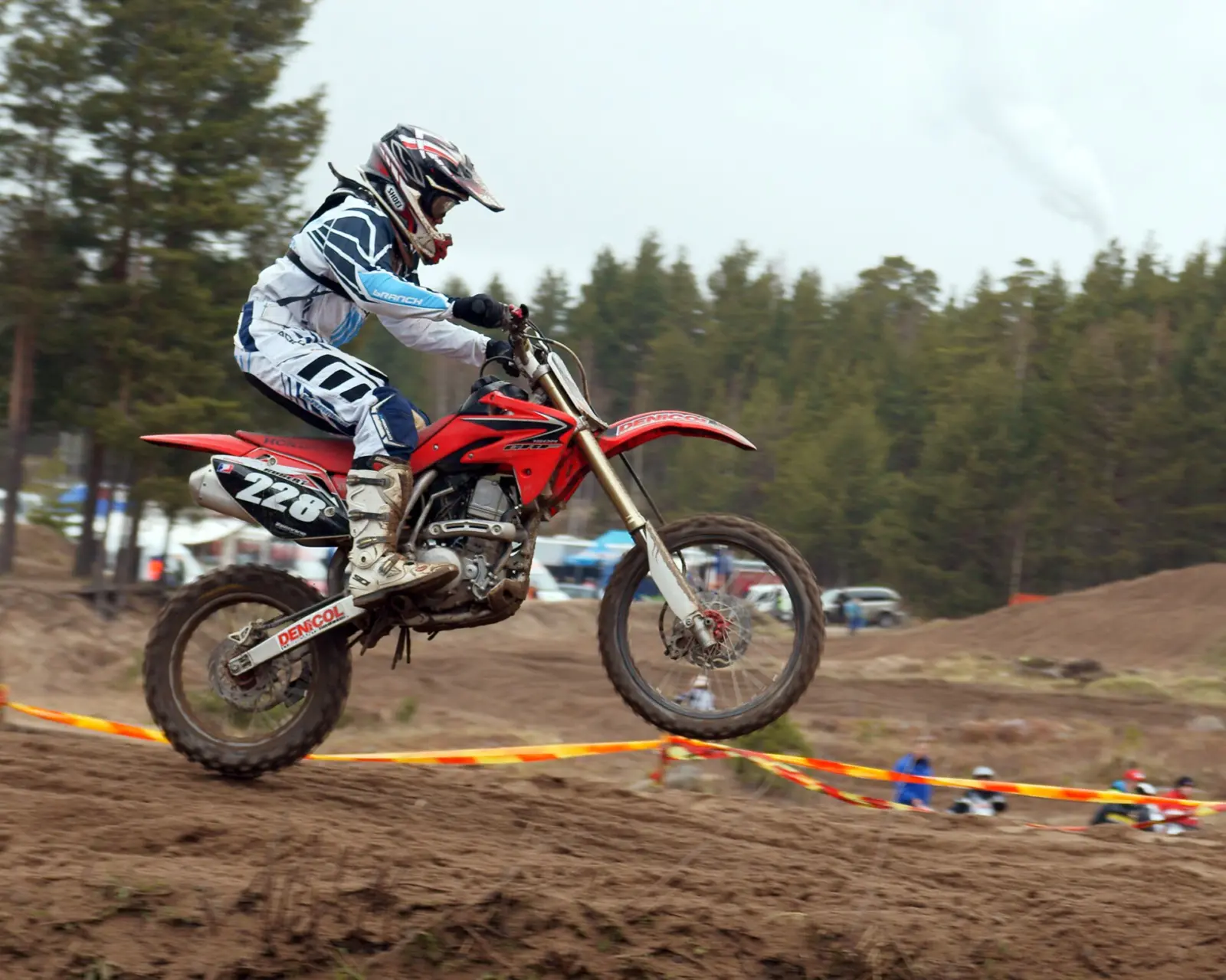 Motocross rider wearing a helmet and boots while jumping a dirt motorcycle