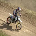 Motocross rider descending a dirt track in protective gear