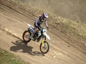 Motocross rider descending a dirt track in protective gear