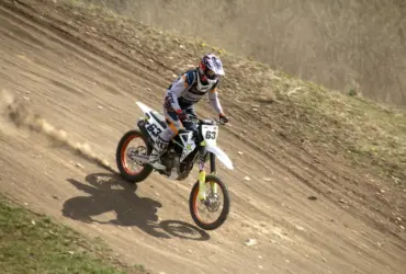 Motocross rider descending a dirt track in protective gear