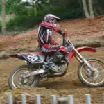 Off-road rider wearing motocross clothing and boots on a dirt track