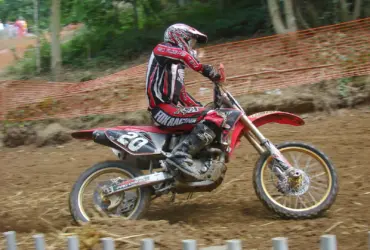 Off-road rider wearing motocross clothing and boots on a dirt track