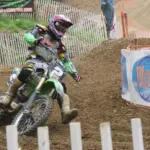 Motocross rider wearing protective off-road clothing on a dirt circuit