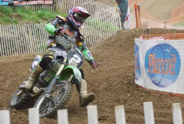 Motocross rider wearing protective off-road clothing on a dirt circuit