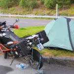Motorcycle touring luggage beside a small campsite