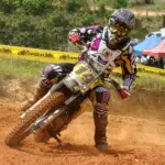 Motocross rider cornering on a dirt track in protective equipment