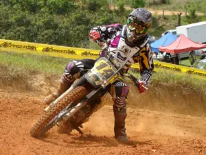 Motocross rider cornering on a dirt track in protective equipment