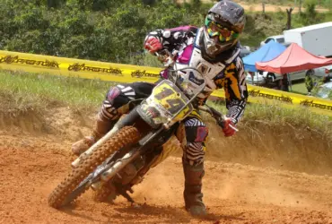 Motocross rider cornering on a dirt track in protective equipment