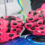 Close-up of red motorcycle racing gloves resting on a fuel tank