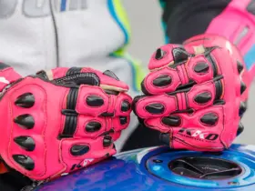 Close-up of red motorcycle racing gloves resting on a fuel tank