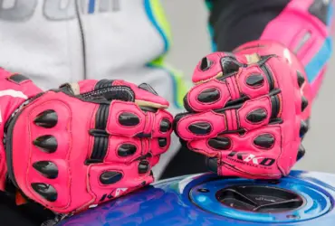 Close-up of red motorcycle racing gloves resting on a fuel tank