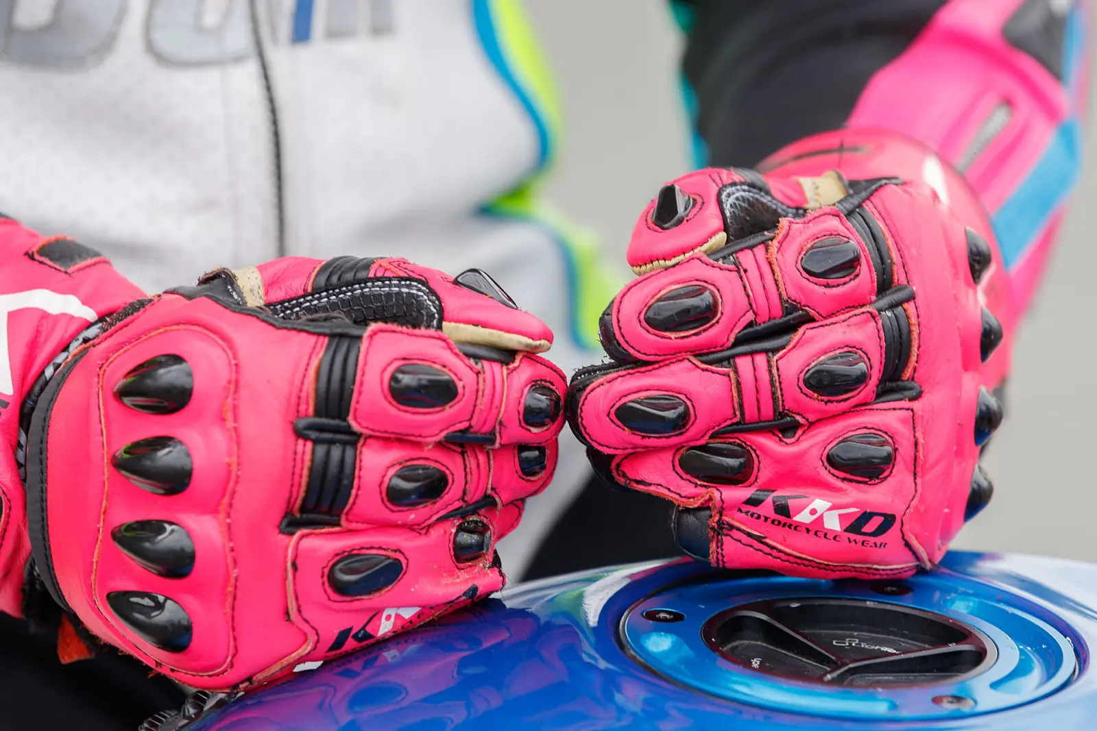 Close-up of red motorcycle racing gloves resting on a fuel tank