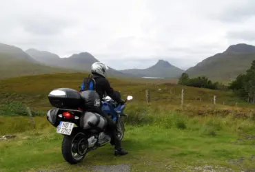 Helmeted touring rider on a motorcycle in a mountainous landscape