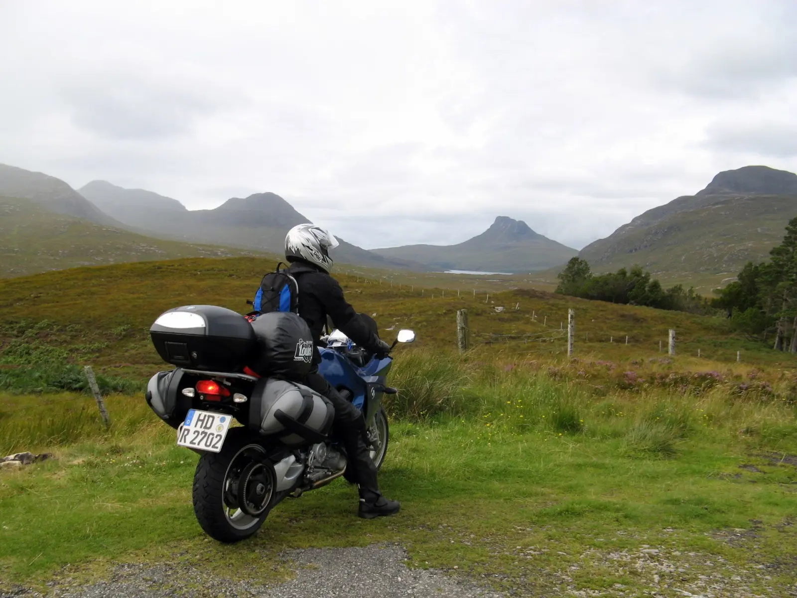 Helmeted touring rider on a motorcycle in a mountainous landscape
