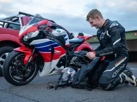 Motorcyclist in protective riding equipment beside a parked motorcycle