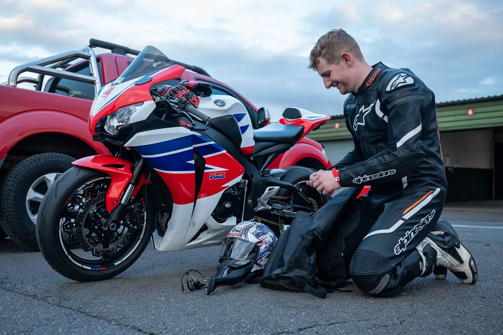 Motorcyclist in protective riding equipment beside a parked motorcycle