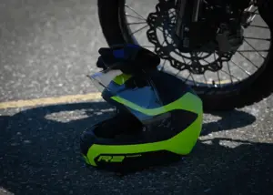 Off-road motorcycle helmet resting beside a motorcycle wheel