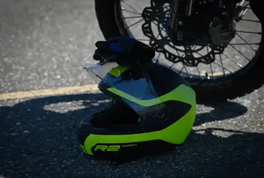 Off-road motorcycle helmet resting beside a motorcycle wheel