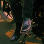 Rider’s boots resting beside a motorcycle footrest