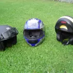 Three different styles of motorcycle helmet arranged on grass