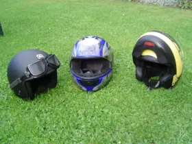 Three different styles of motorcycle helmet arranged on grass
