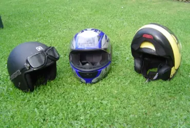Three different styles of motorcycle helmet arranged on grass