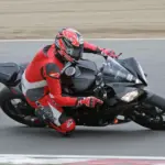 Track rider wearing a red and black leather motorcycle suit