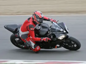 Track rider wearing a red and black leather motorcycle suit