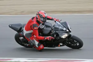 Track rider wearing a red and black leather motorcycle suit