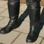 Black motorcycle riding boots worn with protective trousers