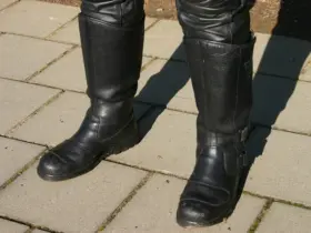 Black motorcycle riding boots worn with protective trousers