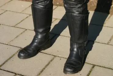 Black motorcycle riding boots worn with protective trousers