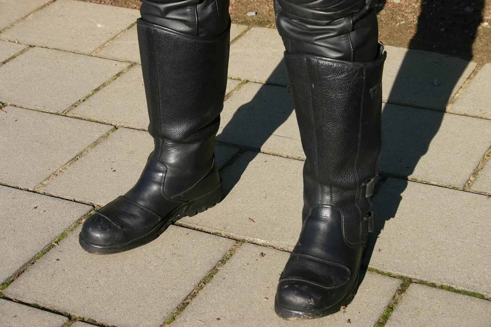 Black motorcycle riding boots worn with protective trousers