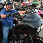 Motorcyclists with helmets and sunglasses beside a touring motorcycle