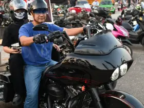 Motorcyclists with helmets and sunglasses beside a touring motorcycle