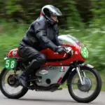 Motorcyclist wearing black leather riding equipment on a red Ducati