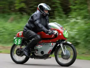 Motorcyclist wearing black leather riding equipment on a red Ducati