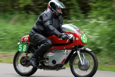 Motorcyclist wearing black leather riding equipment on a red Ducati