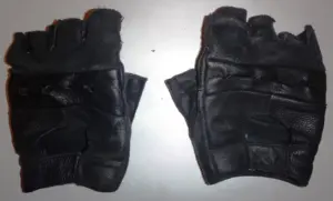 Pair of black short motorcycle gloves on a light background