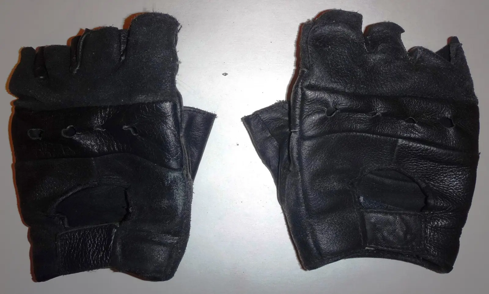 Pair of black short motorcycle gloves on a light background