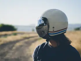 Rider wearing a cream motorcycle helmet with a reflective visor