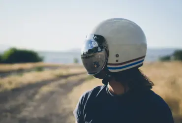 Rider wearing a cream motorcycle helmet with a reflective visor