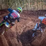 Motocross racers wearing helmets and protective clothing on a dirt track