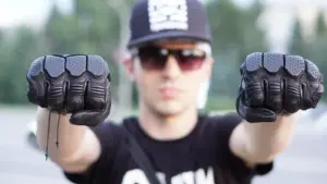 Motorcyclist holding up a pair of black protective gloves