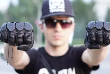 Motorcyclist holding up a pair of black protective gloves