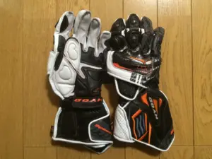 Black and white motorcycle racing gloves shown palm-side up
