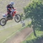 Motocross rider in protective equipment jumping over a track