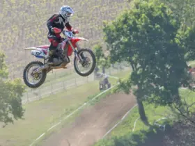 Motocross rider in protective equipment jumping over a track